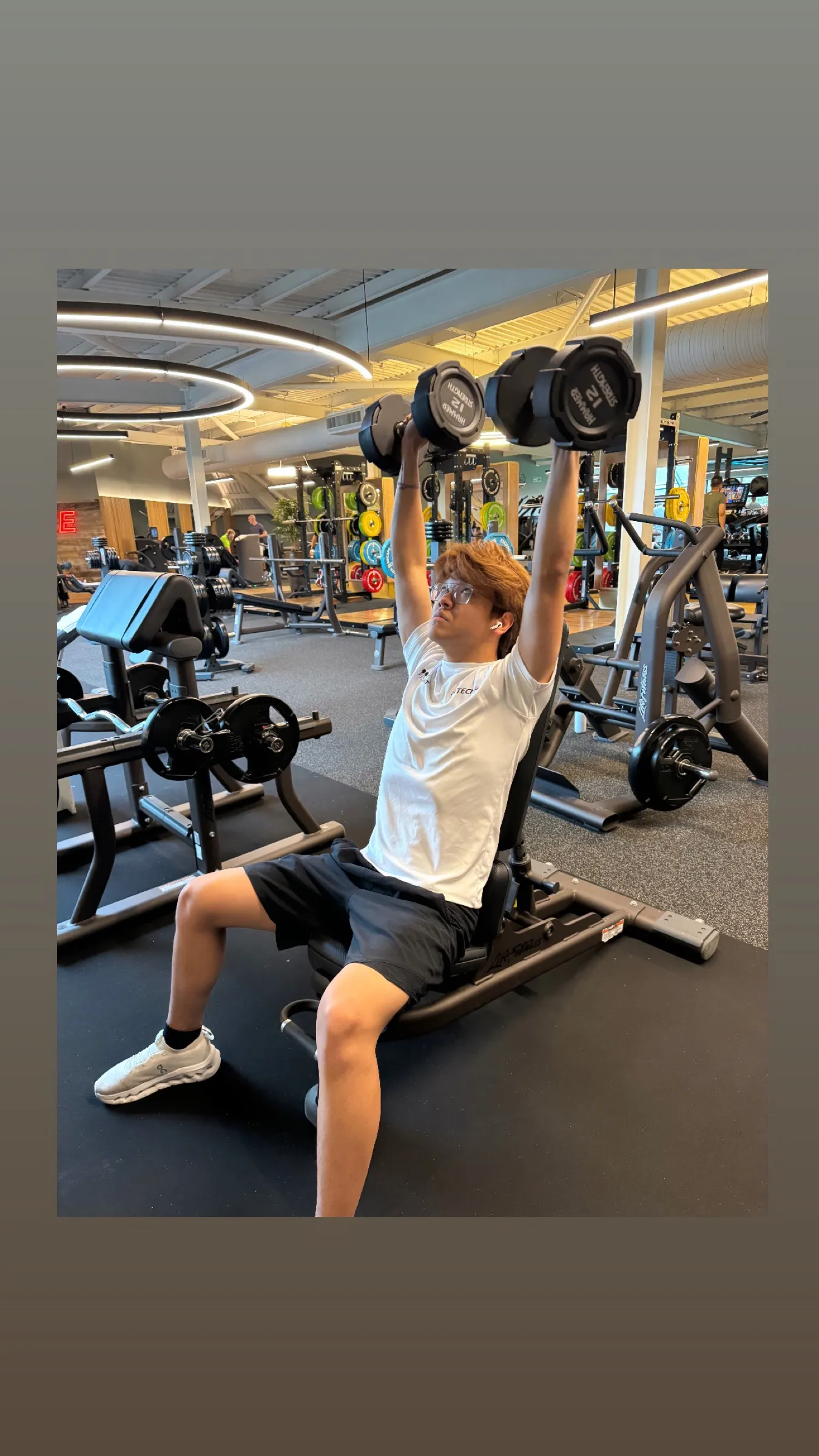 Athlete pressing dumbbells overhead in the gym