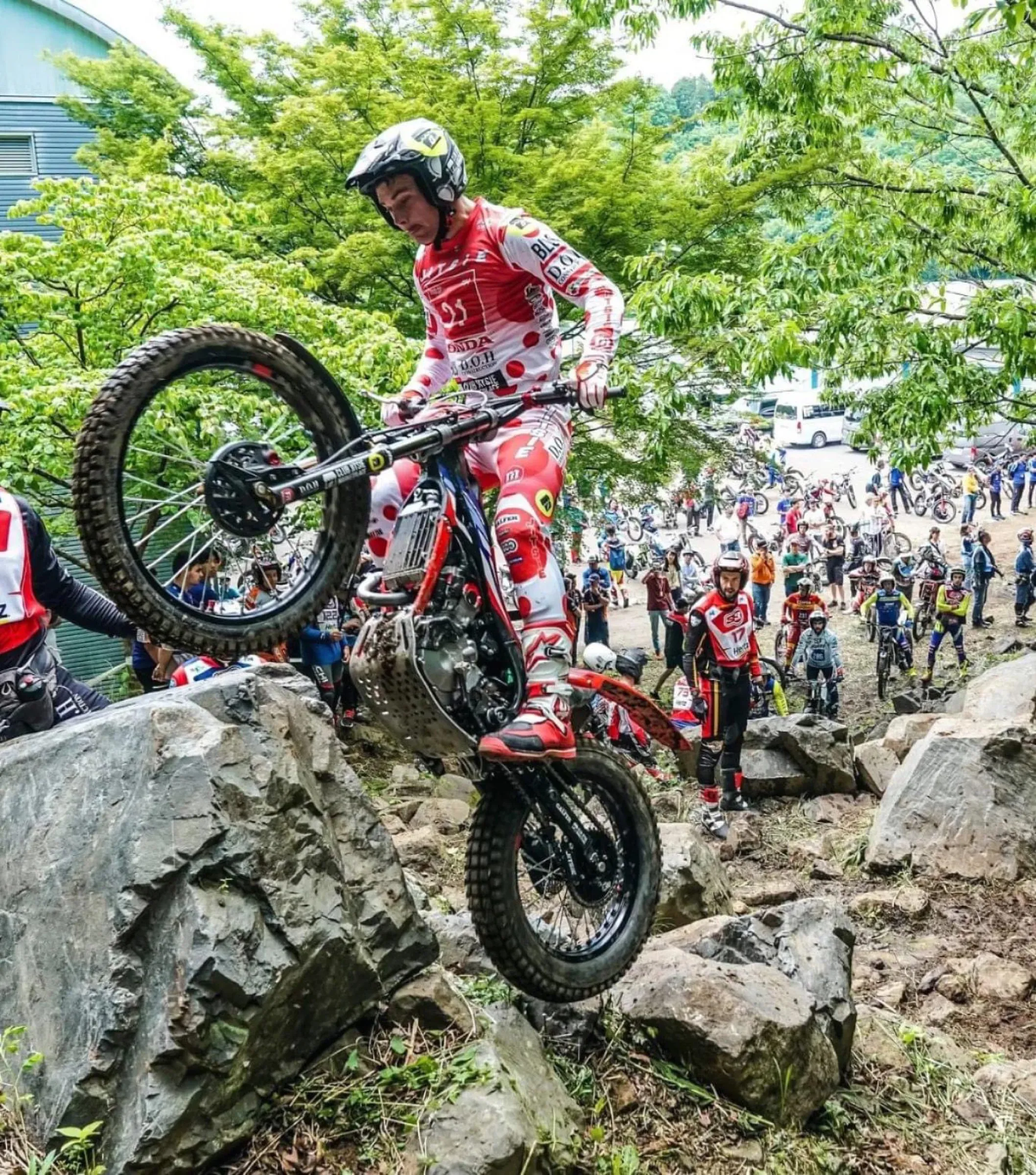 Trials rider climbing a rock section in front of a crowd